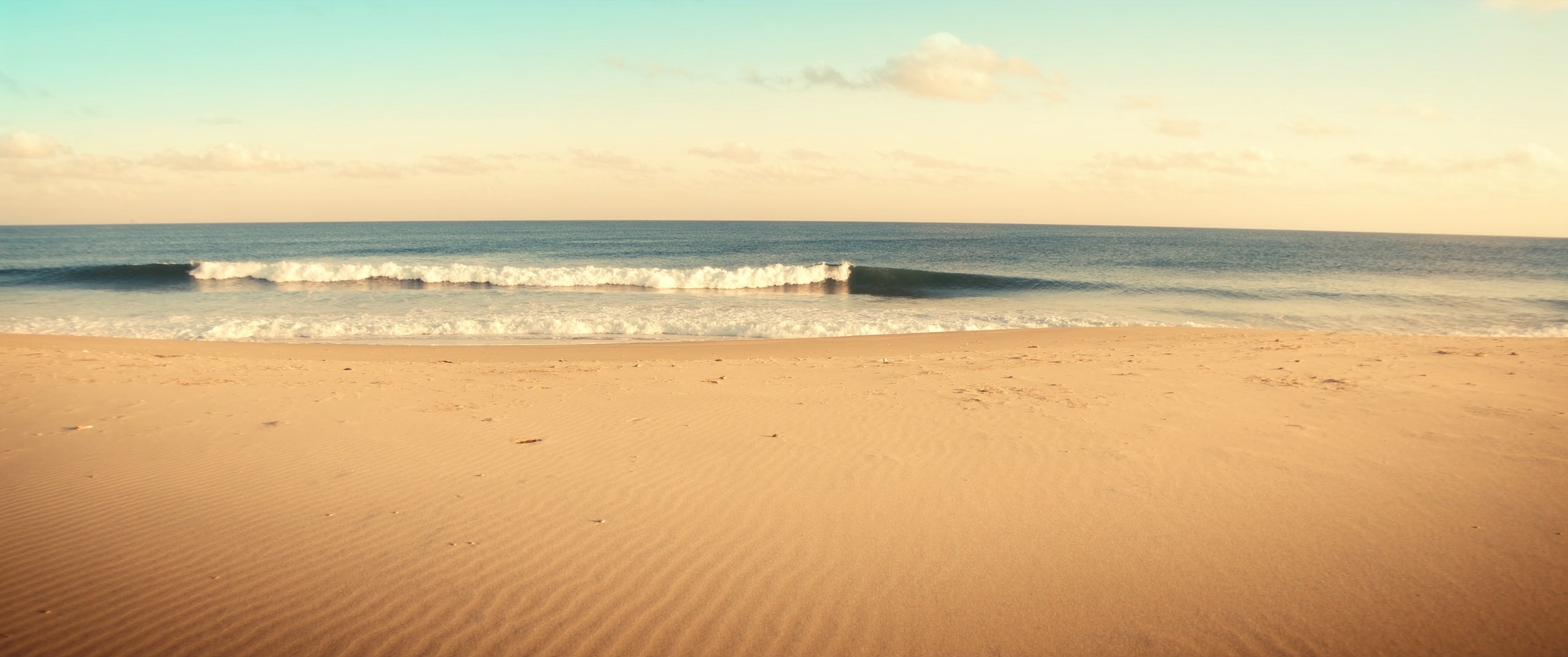 Golden-hour coastal Florida beach with gentle waves rolling onto the sand