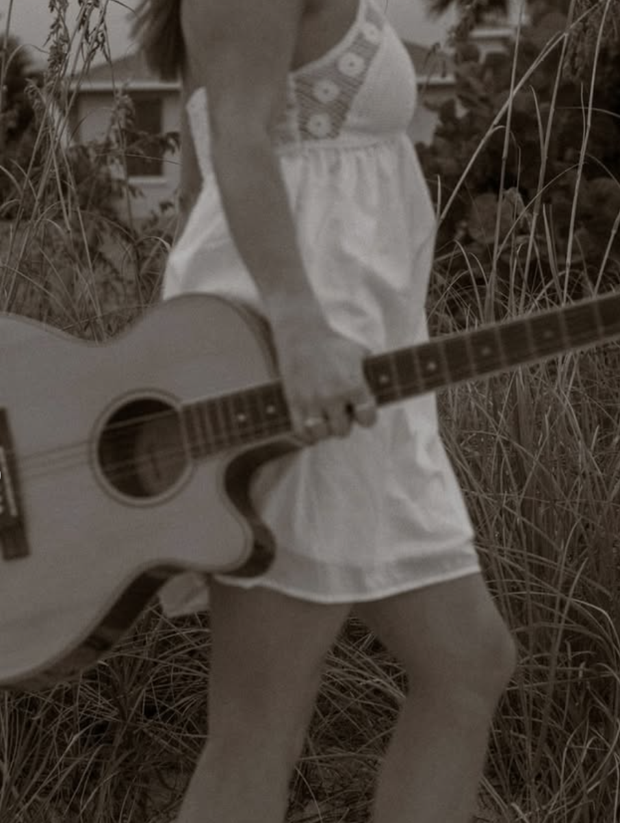 Leanne McGroary portrait with acoustic guitar among coastal sea grass